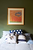 Cat motifs on scatter cushion and in framed picture on green bedroom wall