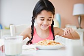 Mixed race girl eating spaghetti