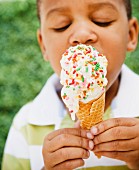Dunkelhäutiger Junge isst ein Eis mit Zuckerstreuseln