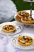 Mini vegetable quiches on a silver stand and plates