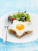Star-shaped Spanish omelette topped with a fried egg, with a side salad