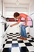 Dark-skinned woman looking in oven