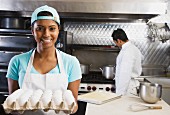 Mixed Race female kitchen worker holding eggs
