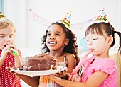 Kindergartenkinder mit Partyhütchen und Geburtstagstorte