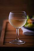 Ein Glas Weißwein auf Holztisch