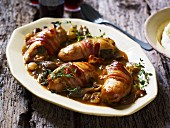 Stuffed rolled chicken breasts wrapped in bacon, with onions and mushrooms