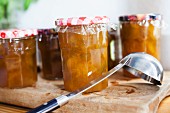 A few jars of greengage jam on a chopping board
