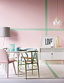 Various pastel chairs around Tulip Table and white sideboard in front of pink wall with green stripes