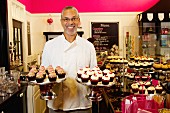 Mann zeigt Kuchenständer mit Cupcakes in der Bäckerei
