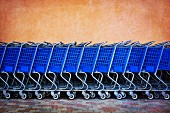 Line of Blue Shopping Carts Against Colorful Wall