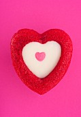 Heart-shaped muffin with white chocolate topping on pink background