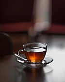 Glass cup of hot tea with steam in a living room table (selective focus)