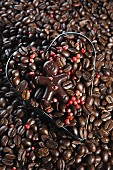 A chocolate figure on top of coffee beans with red peppercorns in a heart-shaped cutter