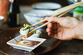 A person eating sushi with chopsticks