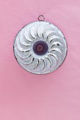 An old Bundt cake mould hanging on a pink wall