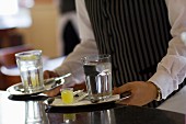 A waiter takes trays with glasses from a bar