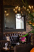 Detail of hotel restaurant with leather sofa, mirror on wall and chandelier