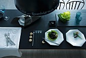 Puristische Tischdeko in Anthrazit und Weiß mit handgeschriebener Menufolge auf dunkler Pendelleuchte