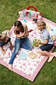 Children eating picnic on floral picnic blanket