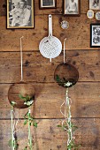 Vintage enamel sieve and rusty metal rings decorated with delicate arrangements of Star-of-Bethlehem hanging on rustic wooden wall