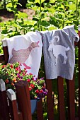 T-shirts with hand-sewn animal motifs hanging on garden fence