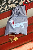 Cloth bag with hand-sewn, appliqué sausage dog motif and dog biscuits on garden bench