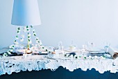 Festive dining table for wedding with garland of white carnations and candlelight below pendant lamp with white lampshade
