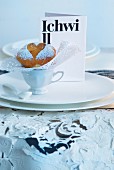 Unconventional menu card and muffin with icing sugar heart motif on wedding table