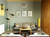 Lounge area with grey-painted walls in modern retro look with small coffee table, animal-skin rug & sofa amongst fifties-style standard lamps