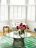 60s table on rug with geometric pattern and armchair in bay window with interior shutters