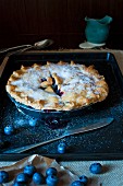 Blueberry Pie on a metal tray with jug of cream and fresh blueberries