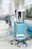 Blaue Nagellackflasche mit Nagelschere und Beauty-Utensilien