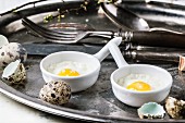 Fried quail eggs with vintage tableware on old metal tray