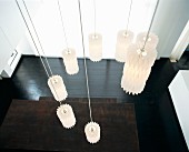 Pendant designer lamps hung in spiral above wooden table and black-varnished wooden floor