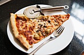 Pizza Slice with Fork and Pizza Cutter on White Plate