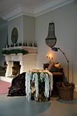 Opulent wreath of mountain lichen on side table and candlelight next to open fireplace with fir garland