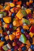 Overhead of colorful fruit salad showing blueberries, mango, plum and kiwi filling the frame
