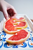 A hand reaching for a slice of grapefruit