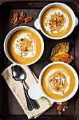 Cream of pumpkin soup garnished with sour cream and pecan nuts