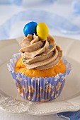 A cupcake decorated with buttercream and coloured chocolate beans