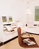 White study with storage space in sideboard; swivel chair and laptop on round table
