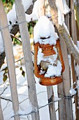 Schneebedeckte Laterne an Gartenzaun hängend