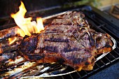 A T-bone steak in an aluminium tray on a barbecue