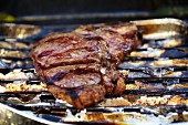 T-Bone-Steak in Aluschale auf Grill (Nahaufnahme)