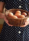 A woman holding a basket of fresh chicken's eggs