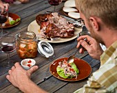 Mann löffelt Sauce auf Schweinefleisch im Salatblatt