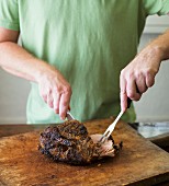A man cutting roast pork on a chopping board