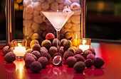 A lychee martini between tea lights and surrounded by fresh lychees
