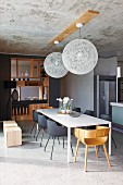 Simple white dining table in open-plan, designer dining area with elegant, purist, wooden partition shelving and concrete ceiling