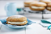 A pumpkin and ginger whoopie pie dusted with icing sugar on a blue napkin (USA)